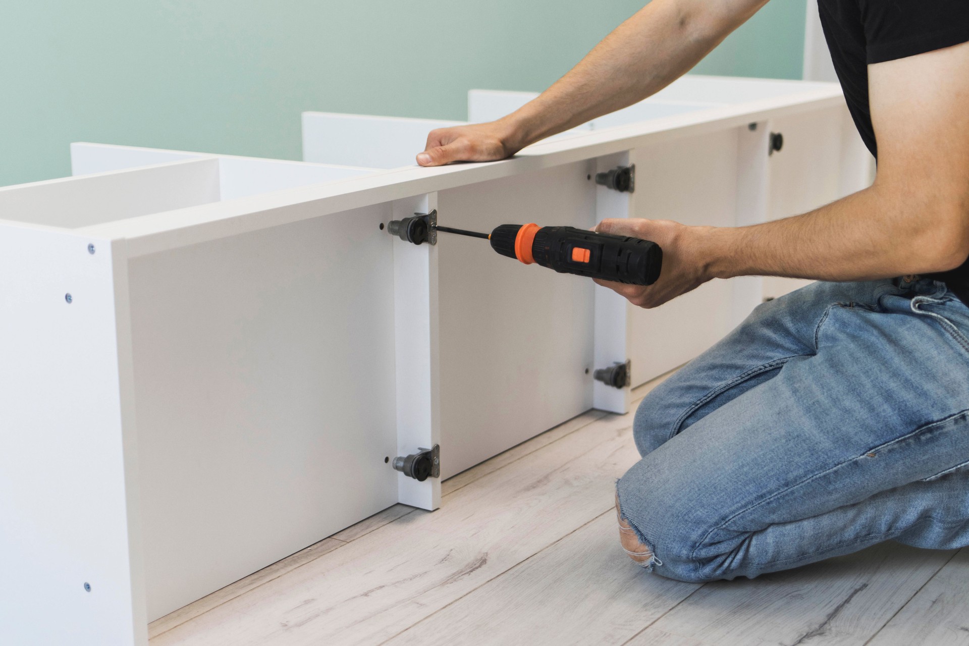 A young craftsman assembles furniture fittings. Screwing the confirmat close-up. Professional furniture assembling. Installation of new furniture. Furniture assembly