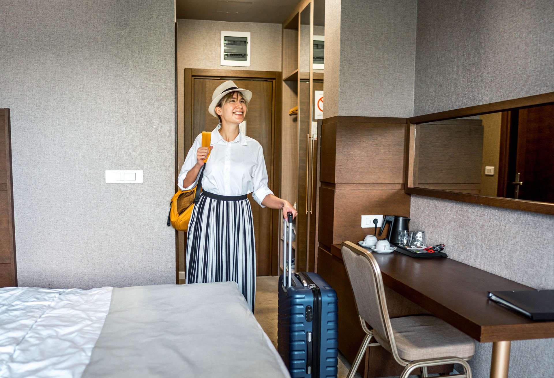 Young woman enters a hotel room with her luggage